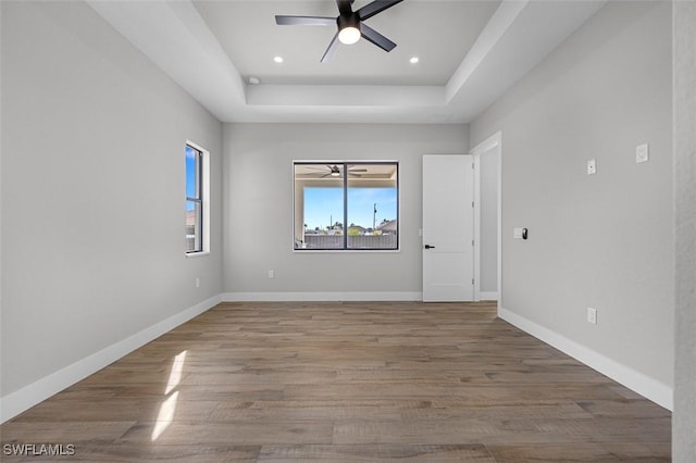 unfurnished room featuring hardwood / wood-style floors, ceiling fan, and a raised ceiling