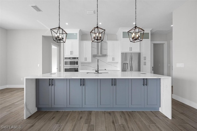 kitchen with a large island, pendant lighting, white cabinets, and stainless steel appliances