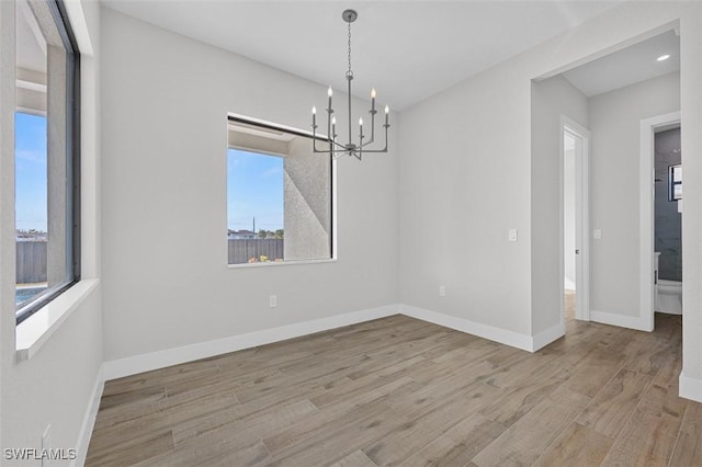 unfurnished dining area with a notable chandelier and light hardwood / wood-style flooring