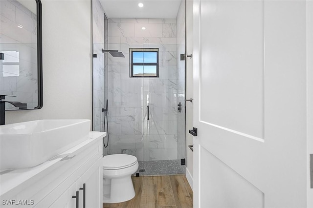 bathroom with wood-type flooring, vanity, toilet, and a shower with shower door