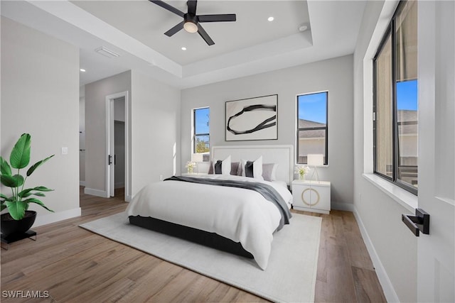 bedroom featuring wood-type flooring, a tray ceiling, and ceiling fan