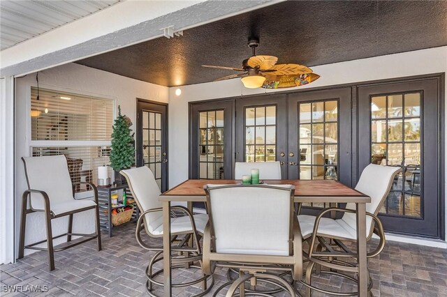 sunroom / solarium featuring ceiling fan, a healthy amount of sunlight, and french doors