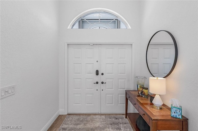 entryway featuring a towering ceiling and hardwood / wood-style flooring