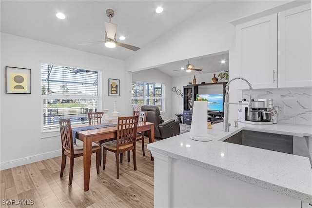 dining room featuring ceiling fan, light hardwood / wood-style flooring, vaulted ceiling, and sink