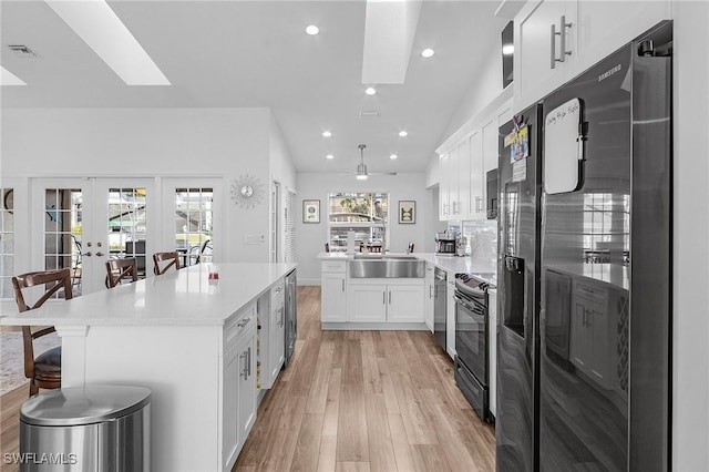 kitchen with white cabinetry, lofted ceiling with skylight, stainless steel appliances, and a wealth of natural light