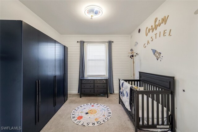 bedroom with black fridge, light carpet, and a crib