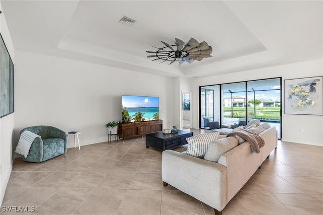 living room with light tile patterned floors, a raised ceiling, and ceiling fan