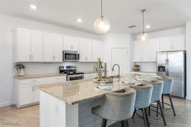 kitchen with a center island with sink, white cabinets, and stainless steel appliances