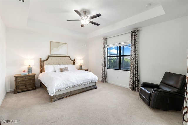 carpeted bedroom with ceiling fan and a tray ceiling