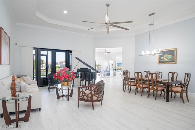 living room featuring french doors, ceiling fan with notable chandelier, light hardwood / wood-style flooring, ornamental molding, and a tray ceiling