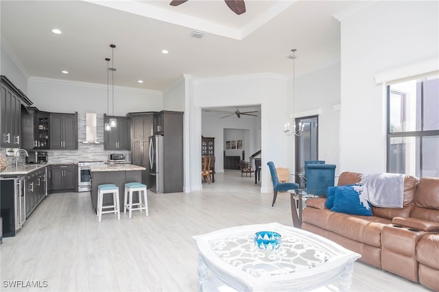 living room featuring light wood-type flooring, an inviting chandelier, ornamental molding, and sink