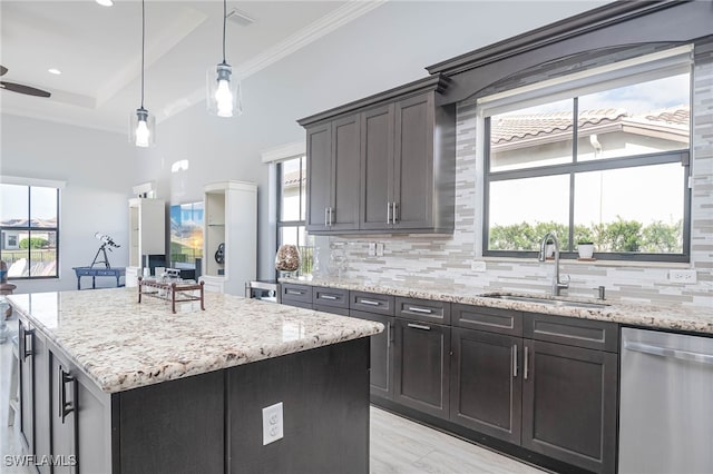 kitchen featuring stainless steel dishwasher, plenty of natural light, a kitchen island, and sink