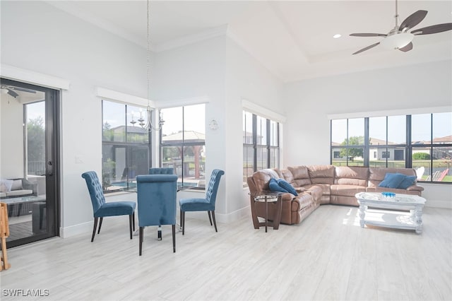 living room with ceiling fan, light hardwood / wood-style flooring, a healthy amount of sunlight, and a high ceiling