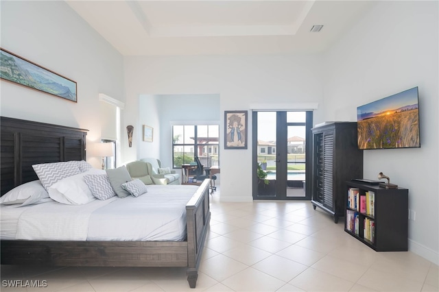 bedroom featuring access to exterior, a towering ceiling, and a tray ceiling