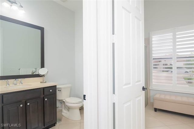 bathroom with toilet, vanity, and tile patterned floors