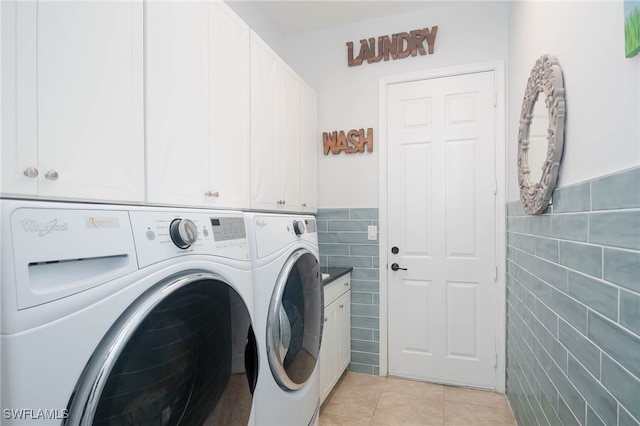 laundry area featuring washer and clothes dryer, light tile patterned flooring, cabinets, and tile walls