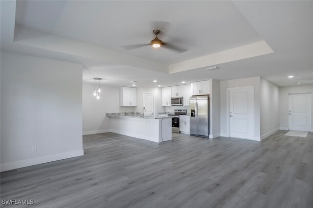 kitchen featuring appliances with stainless steel finishes, white cabinetry, sink, light hardwood / wood-style flooring, and kitchen peninsula