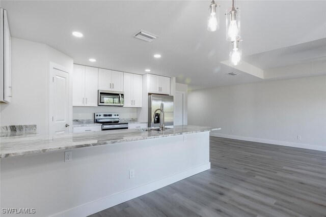 kitchen featuring pendant lighting, white cabinets, appliances with stainless steel finishes, kitchen peninsula, and light stone counters