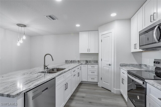 kitchen with kitchen peninsula, sink, white cabinetry, and stainless steel appliances