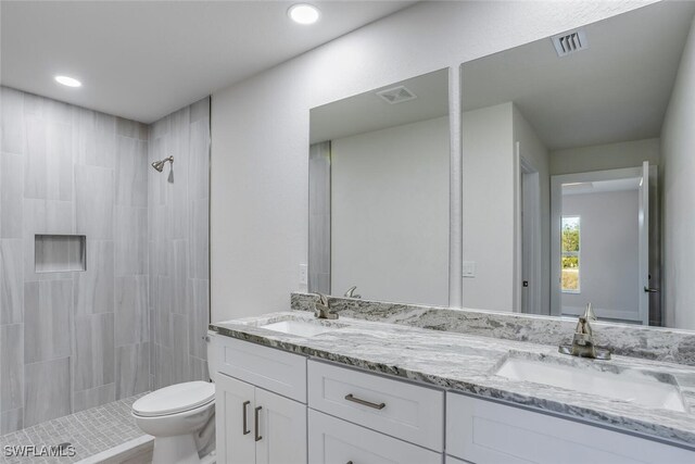 bathroom with vanity, toilet, and tiled shower