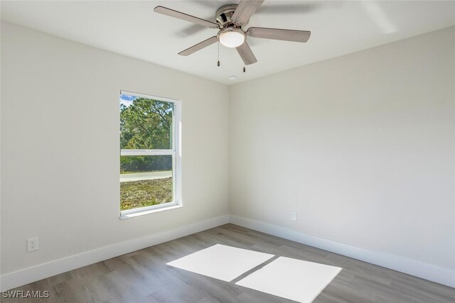 spare room with ceiling fan, light wood-type flooring, and a wealth of natural light