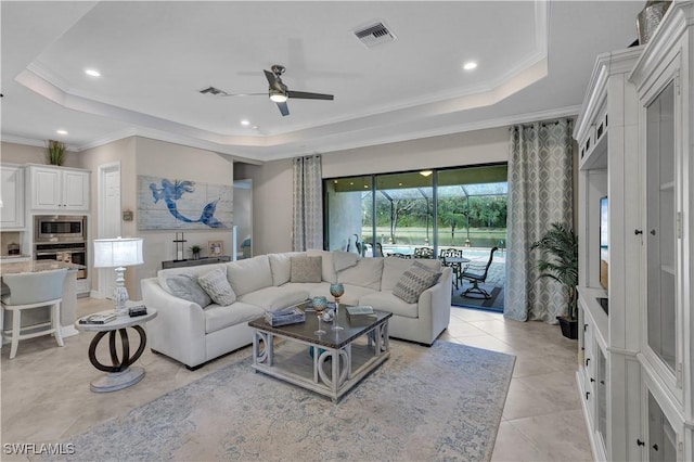 living room featuring a tray ceiling, ceiling fan, light tile patterned flooring, and ornamental molding