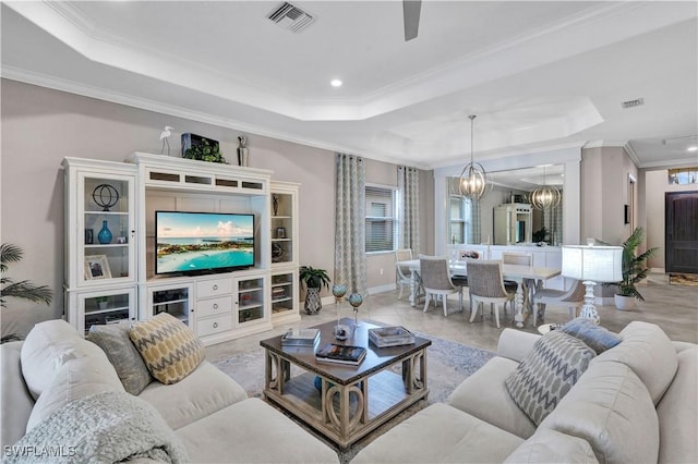 living room featuring a raised ceiling, crown molding, and a chandelier