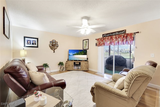 living room with ceiling fan, a textured ceiling, and light hardwood / wood-style flooring