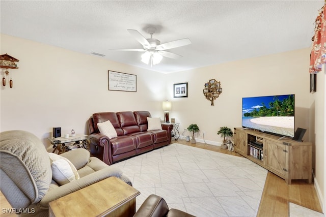 living room with a textured ceiling, light hardwood / wood-style floors, and ceiling fan