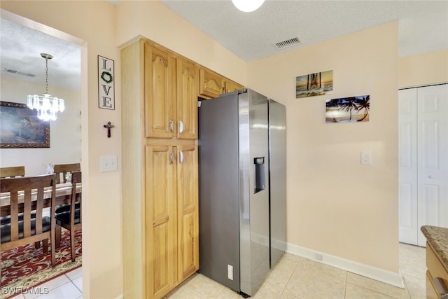 kitchen with stainless steel fridge with ice dispenser, a textured ceiling, decorative light fixtures, and light tile patterned floors