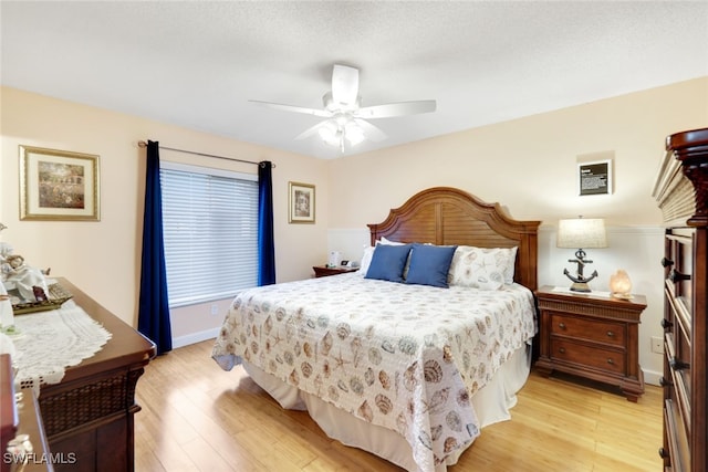 bedroom with ceiling fan, light wood-type flooring, and a textured ceiling