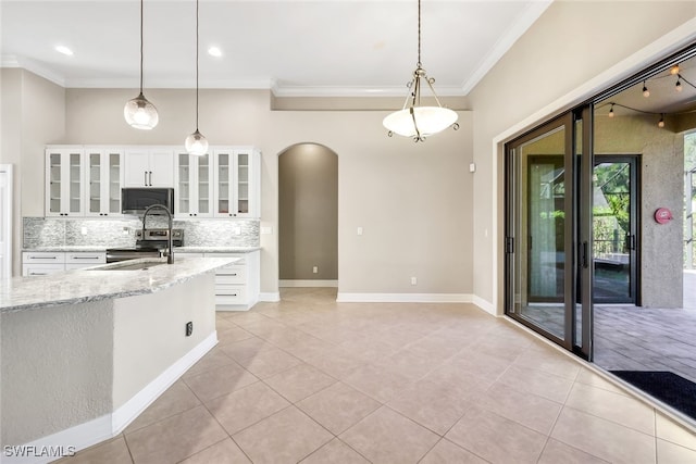 kitchen featuring appliances with stainless steel finishes, backsplash, light stone counters, white cabinetry, and hanging light fixtures