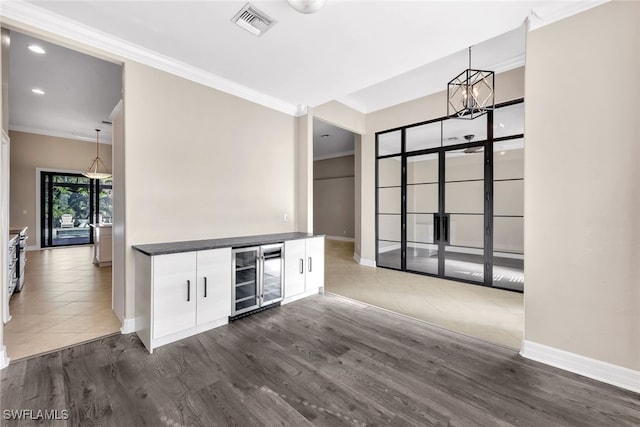 interior space with wine cooler, ornamental molding, dark hardwood / wood-style floors, and a notable chandelier