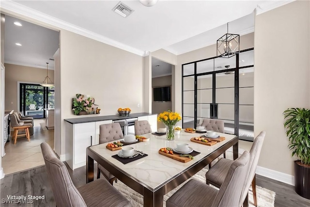 dining space featuring hardwood / wood-style floors, a notable chandelier, and crown molding