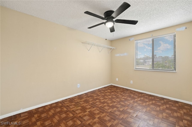 empty room featuring dark parquet flooring, a textured ceiling, and ceiling fan