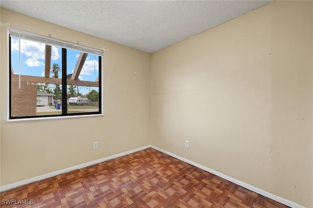 spare room featuring parquet floors and a textured ceiling