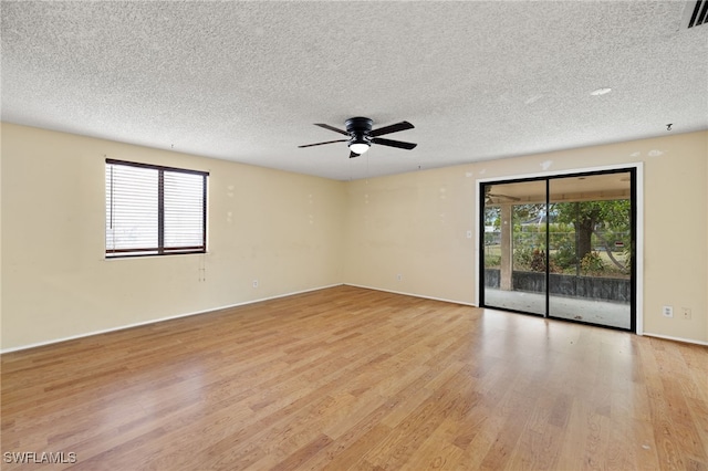 spare room featuring plenty of natural light, ceiling fan, light wood-type flooring, and a textured ceiling