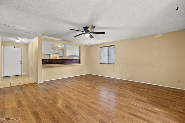 unfurnished living room with ceiling fan, light hardwood / wood-style floors, and a textured ceiling