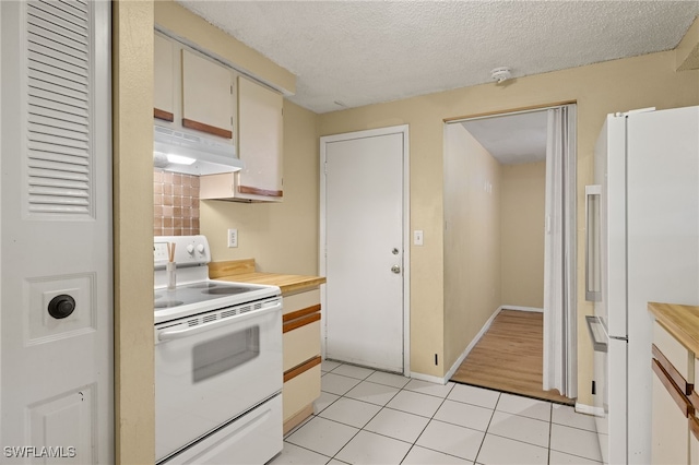 kitchen with white appliances, a textured ceiling, and light tile patterned floors