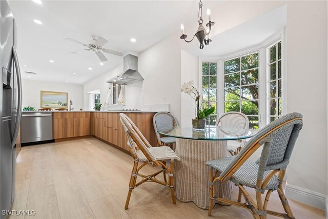 dining area featuring ceiling fan with notable chandelier and light hardwood / wood-style floors