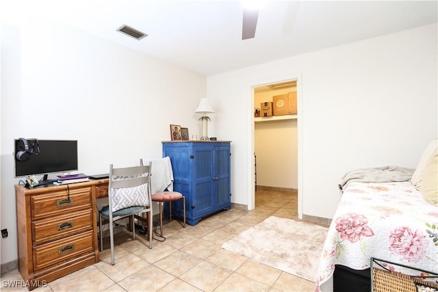 tiled bedroom featuring ceiling fan and a walk in closet