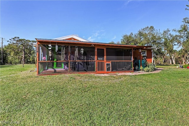 rear view of house with a lawn and a sunroom