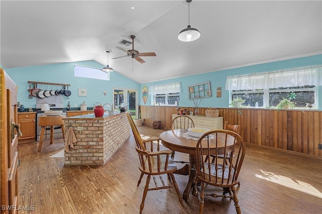 dining room with wood walls, ceiling fan, light hardwood / wood-style floors, and lofted ceiling