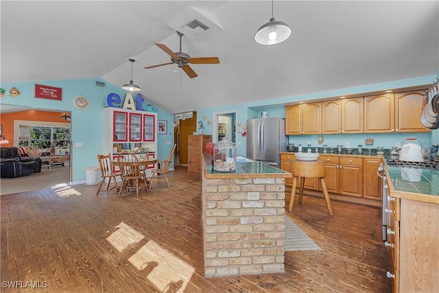 kitchen with lofted ceiling, hanging light fixtures, hardwood / wood-style flooring, appliances with stainless steel finishes, and tile counters