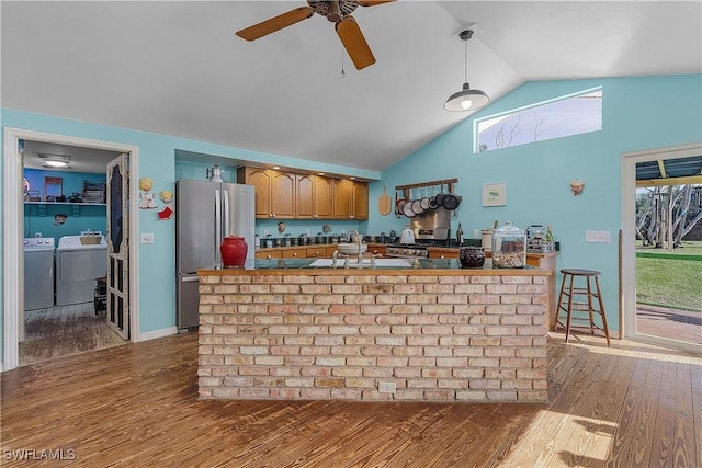 bar featuring sink, stainless steel fridge, hardwood / wood-style floors, decorative light fixtures, and vaulted ceiling