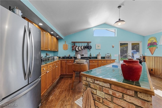 kitchen featuring tile countertops, pendant lighting, vaulted ceiling, dark hardwood / wood-style floors, and appliances with stainless steel finishes