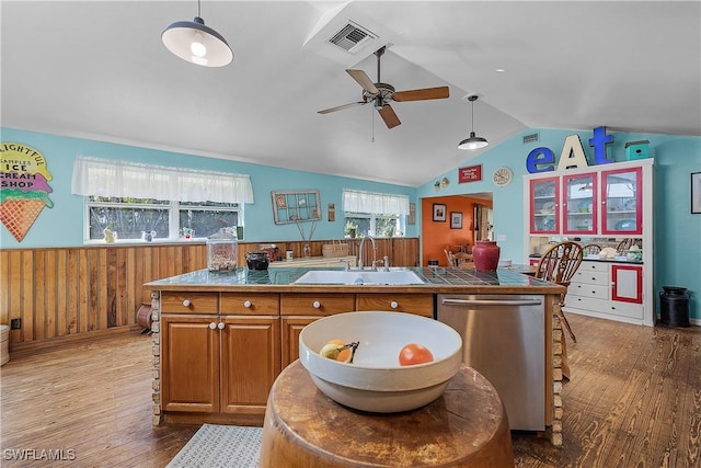 kitchen featuring sink, stainless steel dishwasher, an island with sink, wood-type flooring, and vaulted ceiling