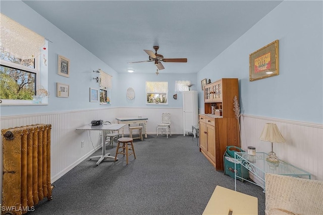 misc room featuring dark colored carpet, radiator, and ceiling fan