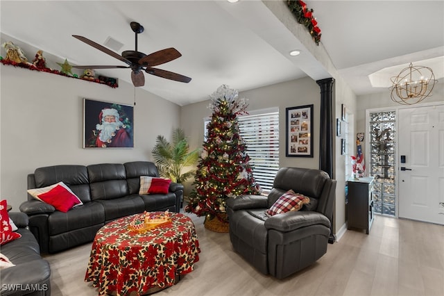 living room with ceiling fan with notable chandelier, light hardwood / wood-style floors, and lofted ceiling