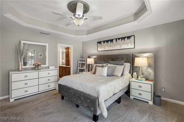 carpeted bedroom featuring a raised ceiling, connected bathroom, and ceiling fan